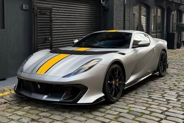 Silver Ferrari 812 with yellow stripes on a cobbled street
