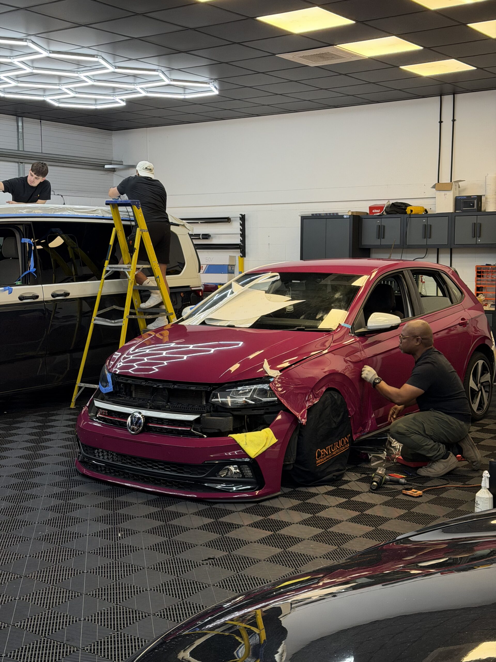 Wrapd Studios team working on a red car in the studio