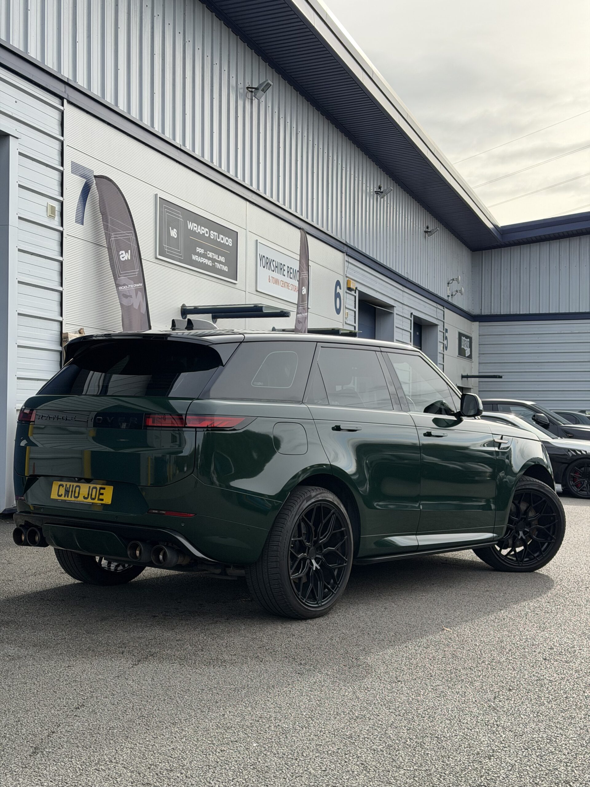 Green Range Rover Sport rear three-quarter with dark tinted rear windows